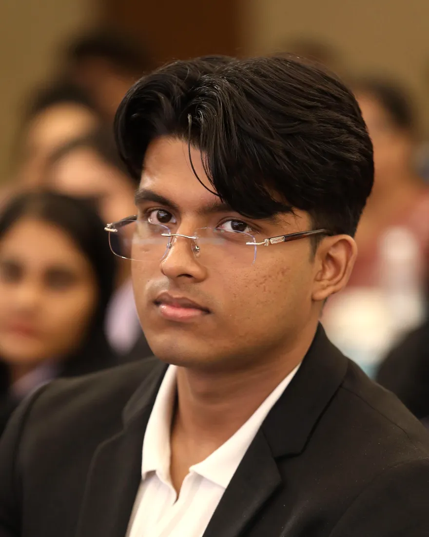 Jonah Joy, Founder and CEO of Brightside English, in glasses and a dark jacket, listening from the audience